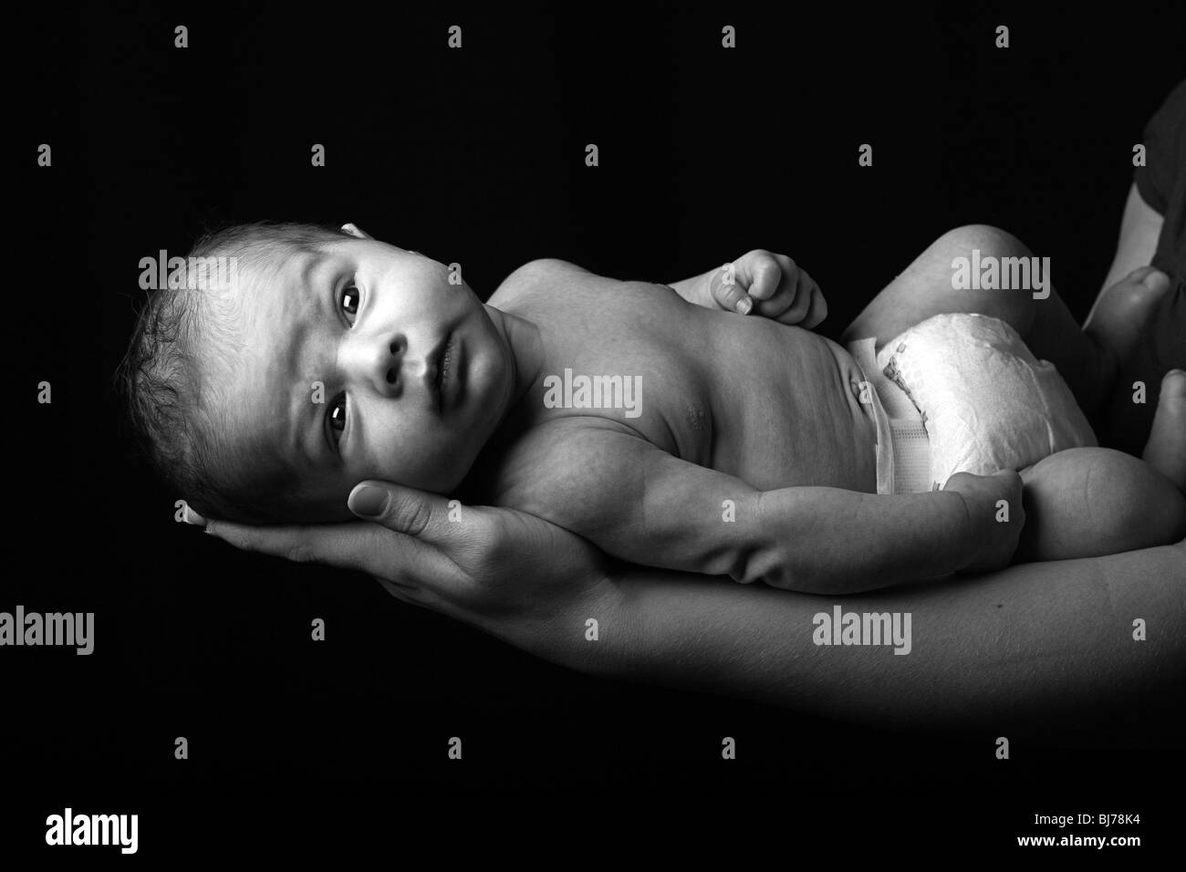 a newly born child gazes at the camera in a low key dramatic setting Stock Photo