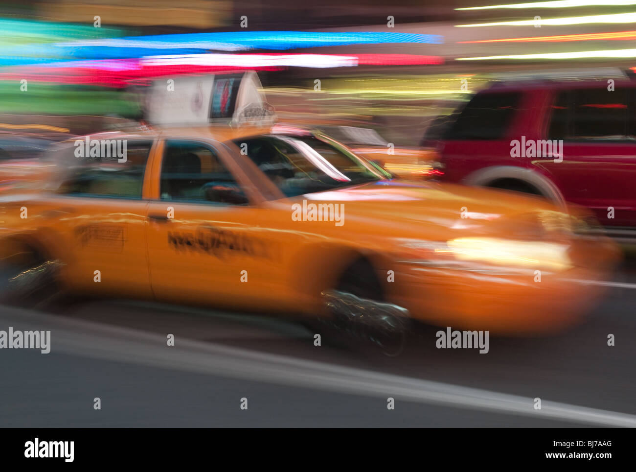 A yellow taxi cab is a blur as it rushes through the lights of Times Square at night in New York City. Stock Photo