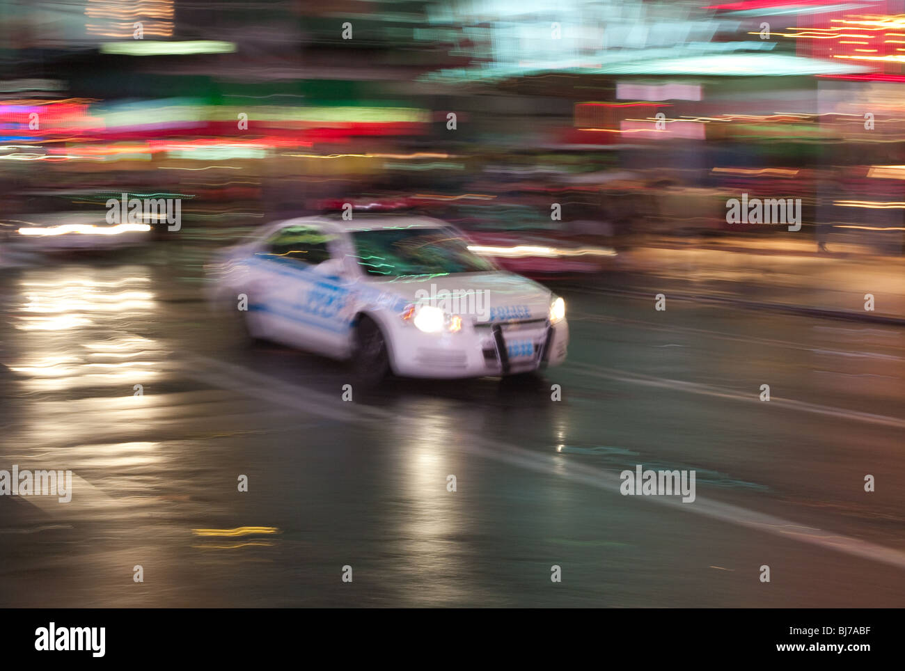Motion blurred abstraction of NYPD police car rushing through Times Square in the rain Stock Photo