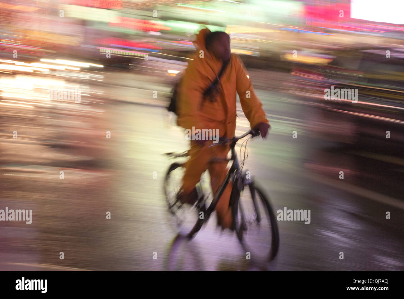 A cyclist rides through the lights of Times Square at night in New York City. Stock Photo