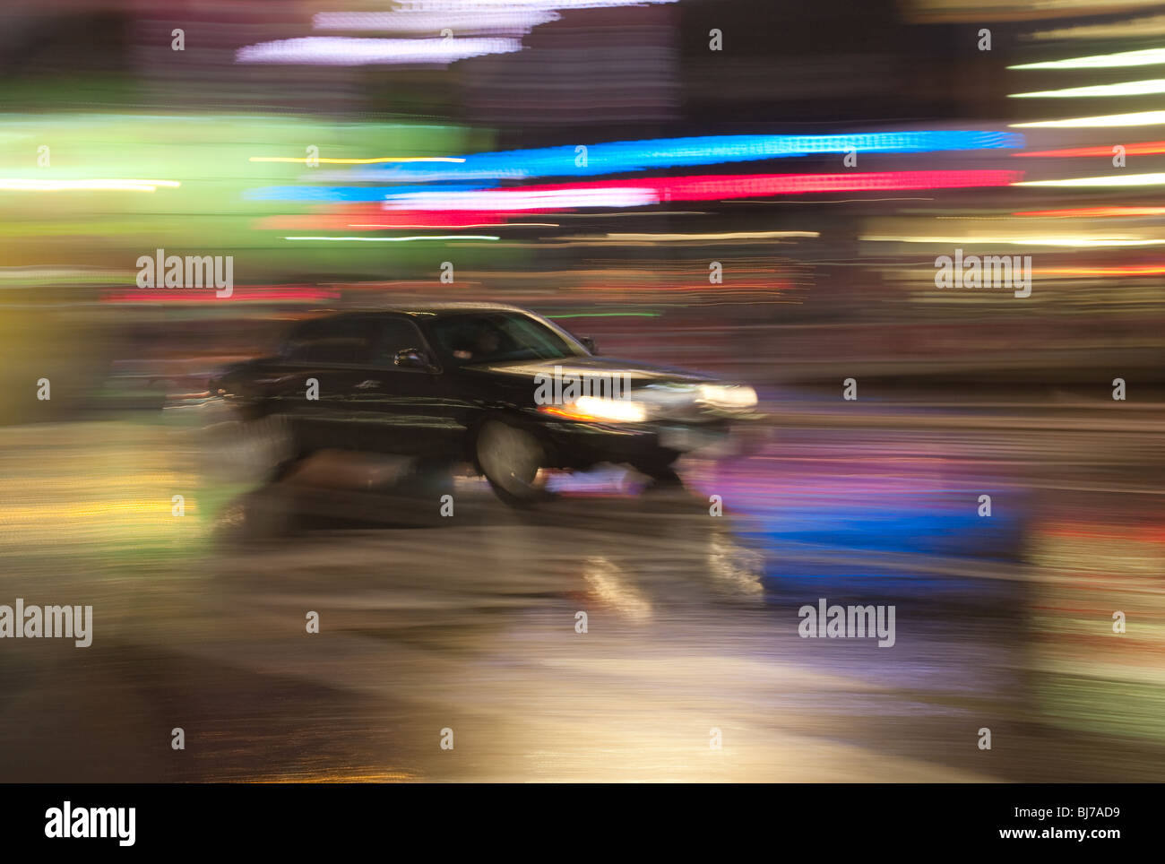 A black limousine is a blur as it rushes through the lights of Times Square at night in New York City. Stock Photo