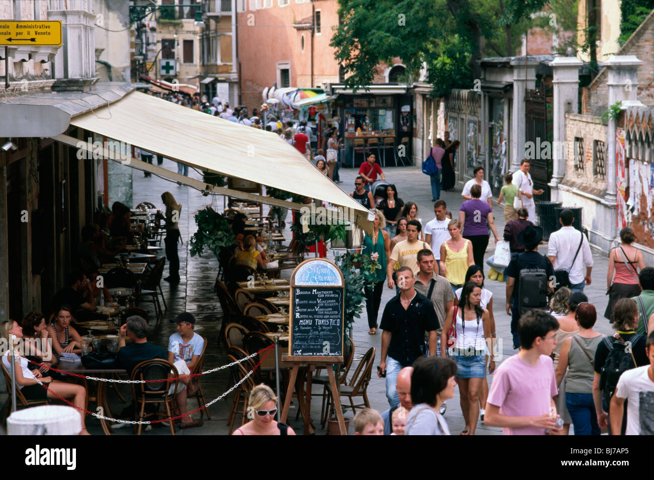 Venice, July 2008 -- Tourists walking past outdoor restaurant. Stock Photo
