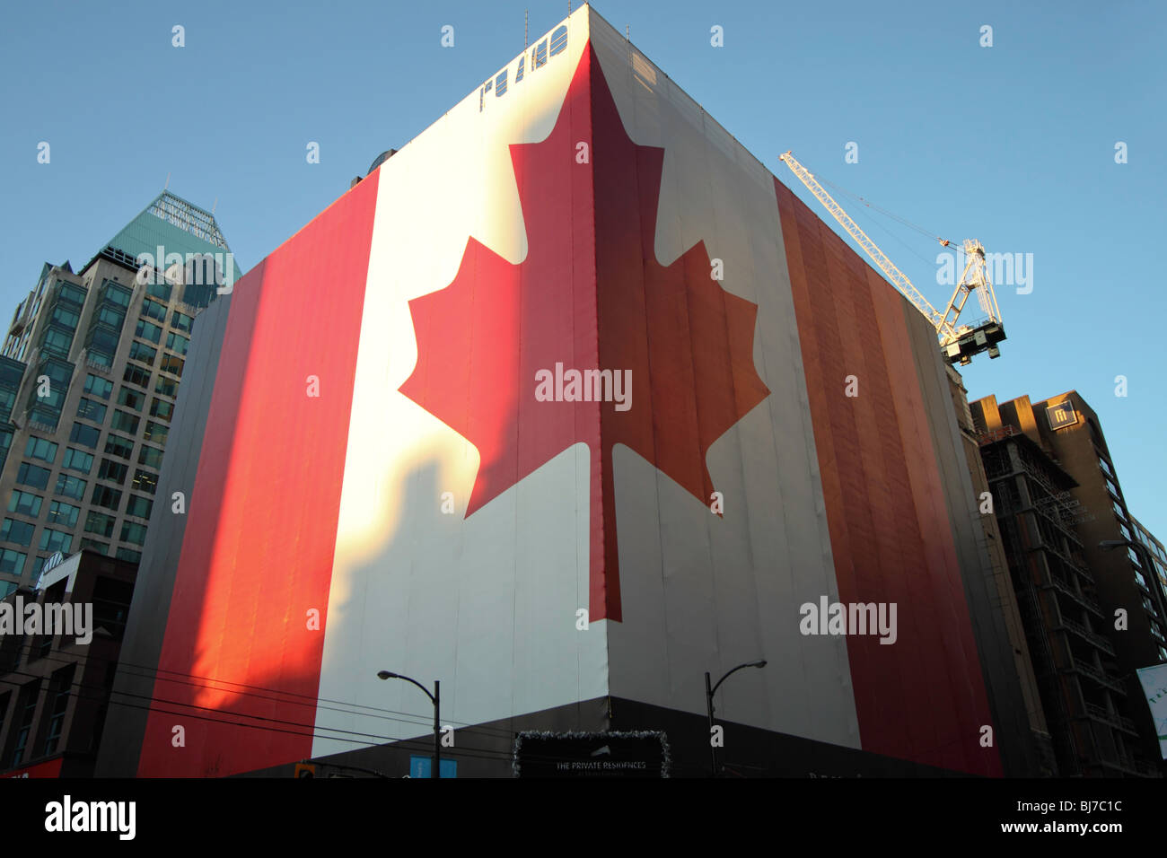 A Huge building wrapped on two sides with the Canadian National flag on the corner of Georgia street and Howe street. Stock Photo