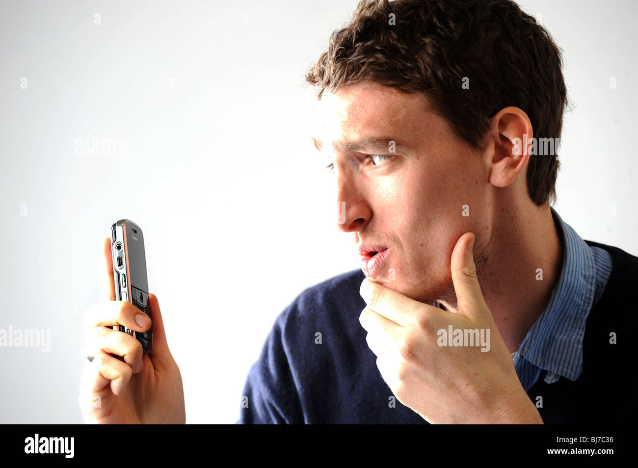 Young man in his twenties holding a Blackberry mobile telephone - posed by model Stock Photo