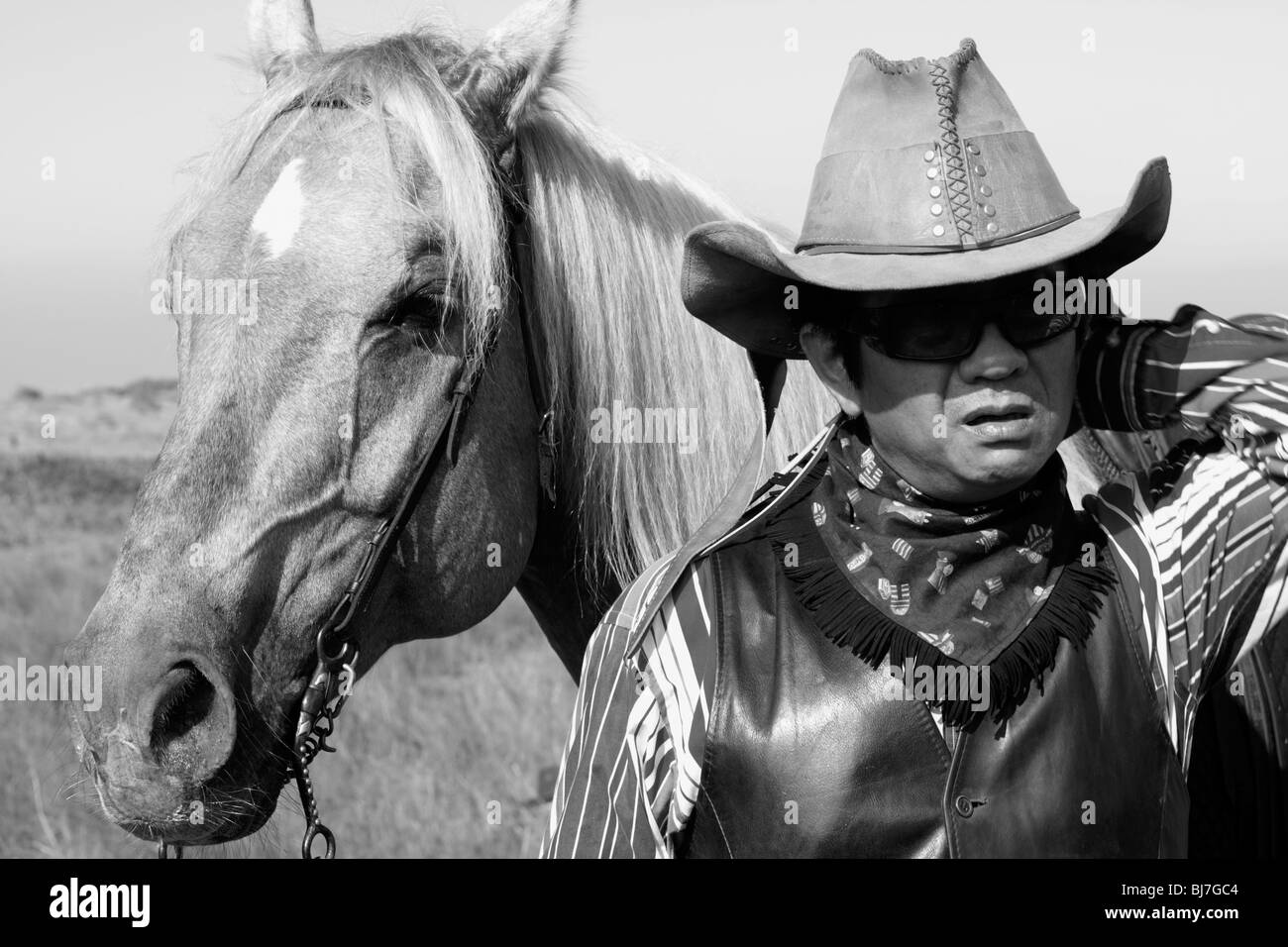 A horse rider looking confused next to his horse his horse. Stock Photo