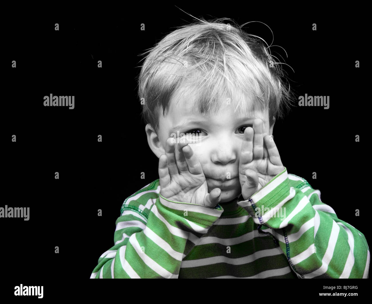 Little boy showing hands on black background, monochrome picture with only color green Stock Photo