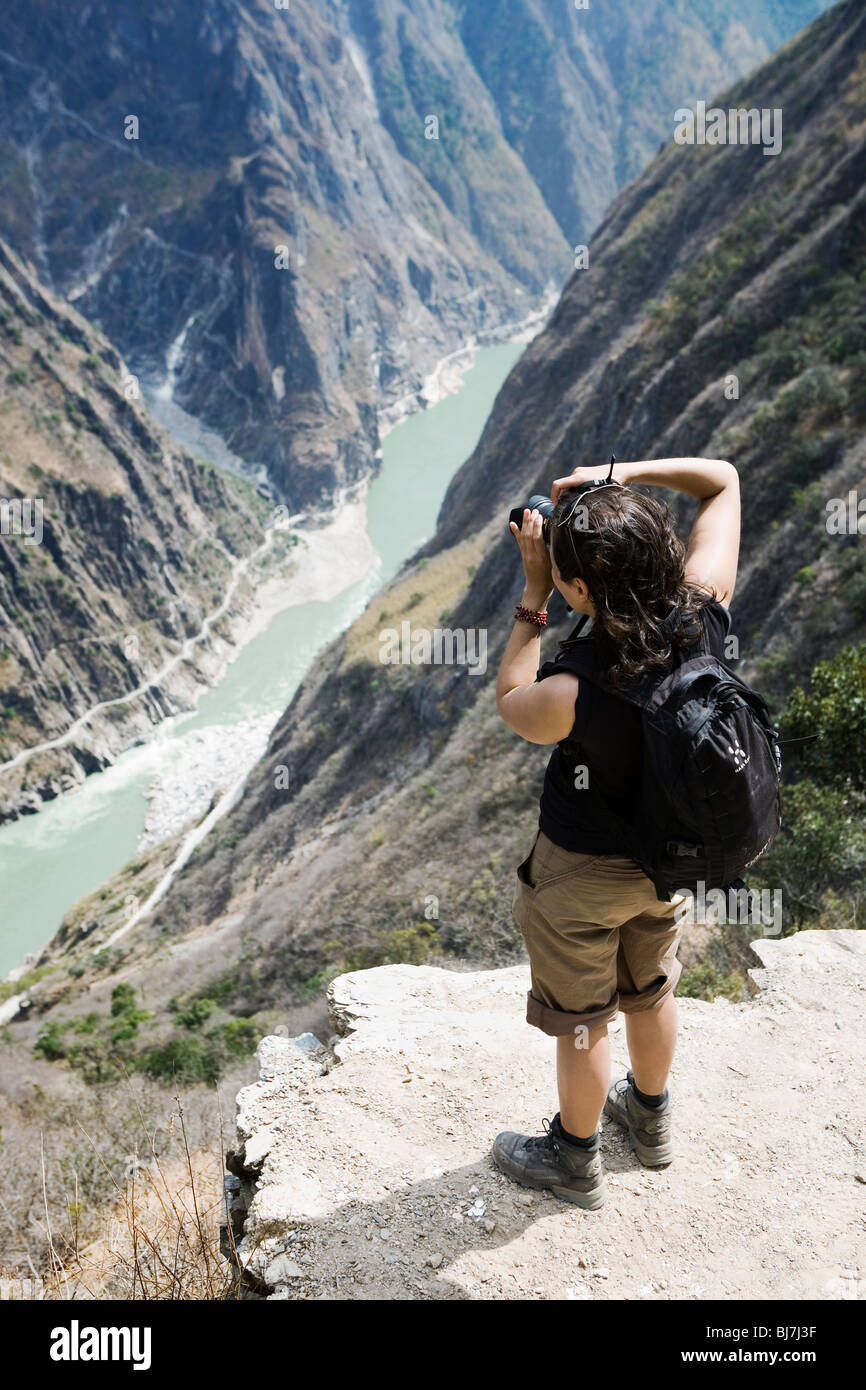 Trekker taking photos at Tiger Leaping Gorge in Yunnan province, China. Stock Photo