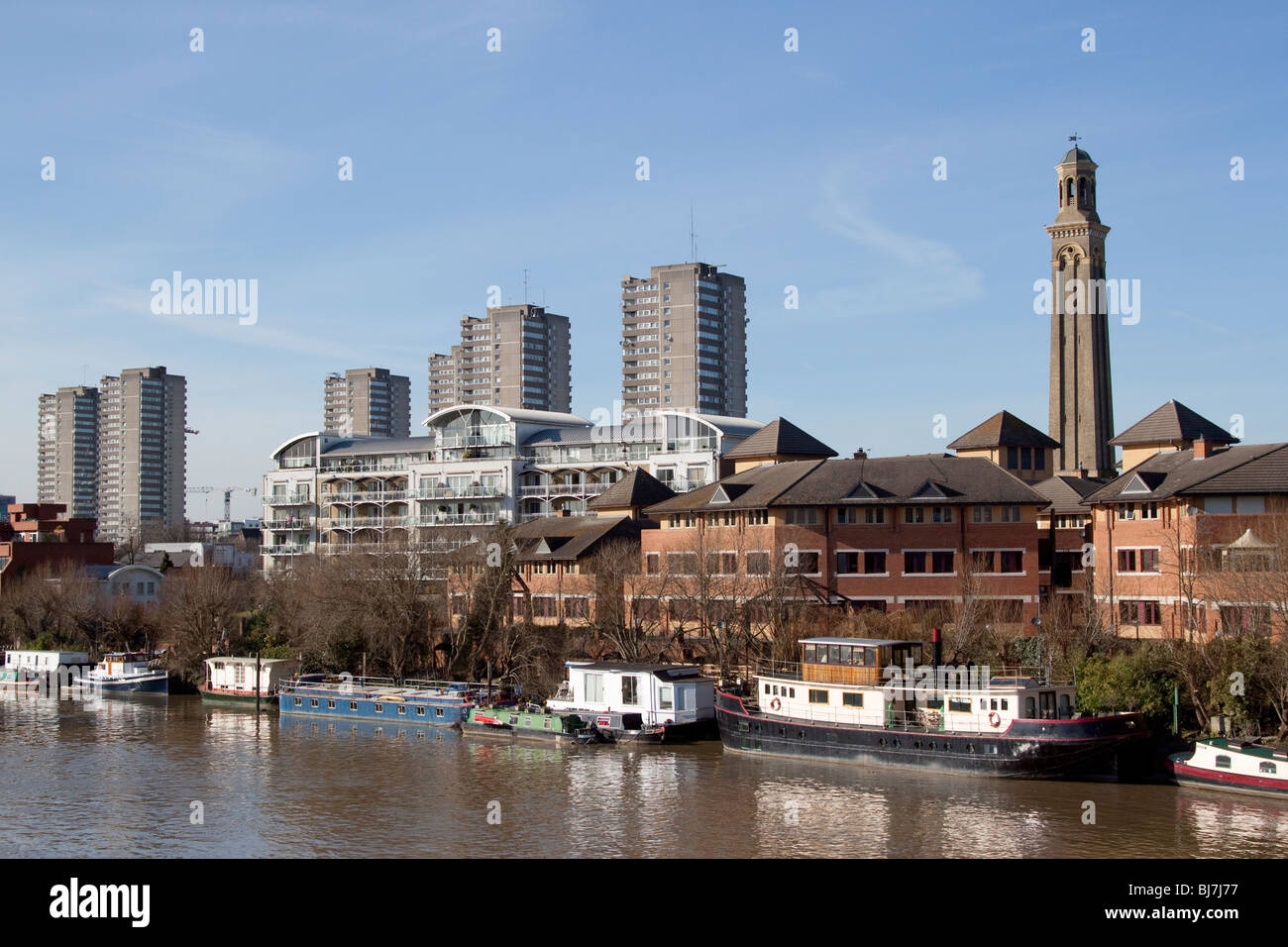 Barges moored and residential boats afloat on the River Thames at Brentford Stock Photo