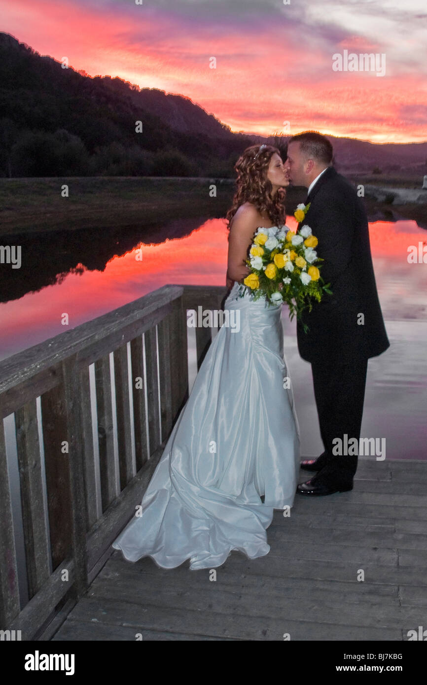 Bride and groom kiss at a lake at sunset Stock Photo - Alamy