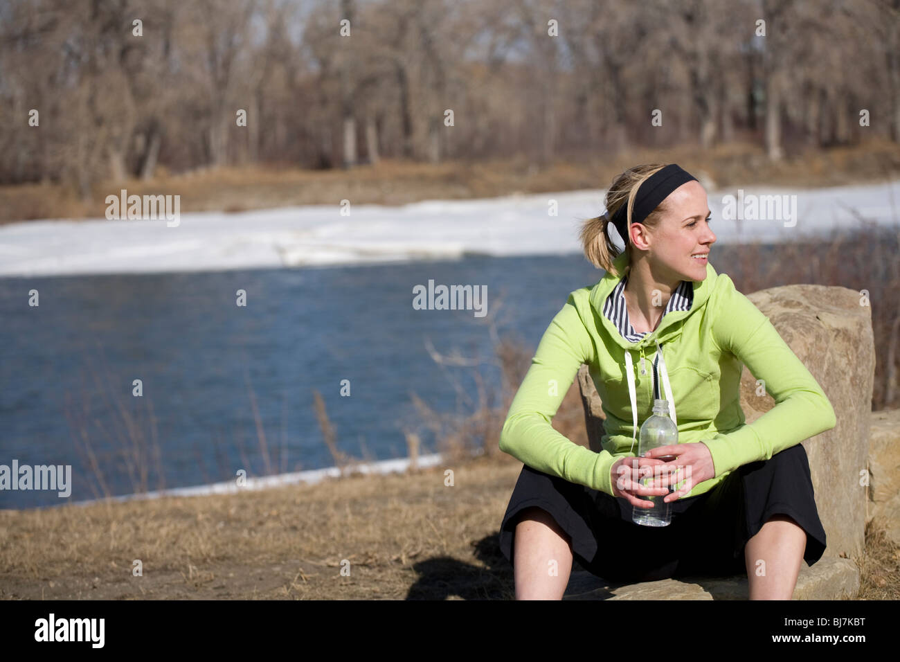 Woman relaxing  on a rock with a bottle of water Stock Photo