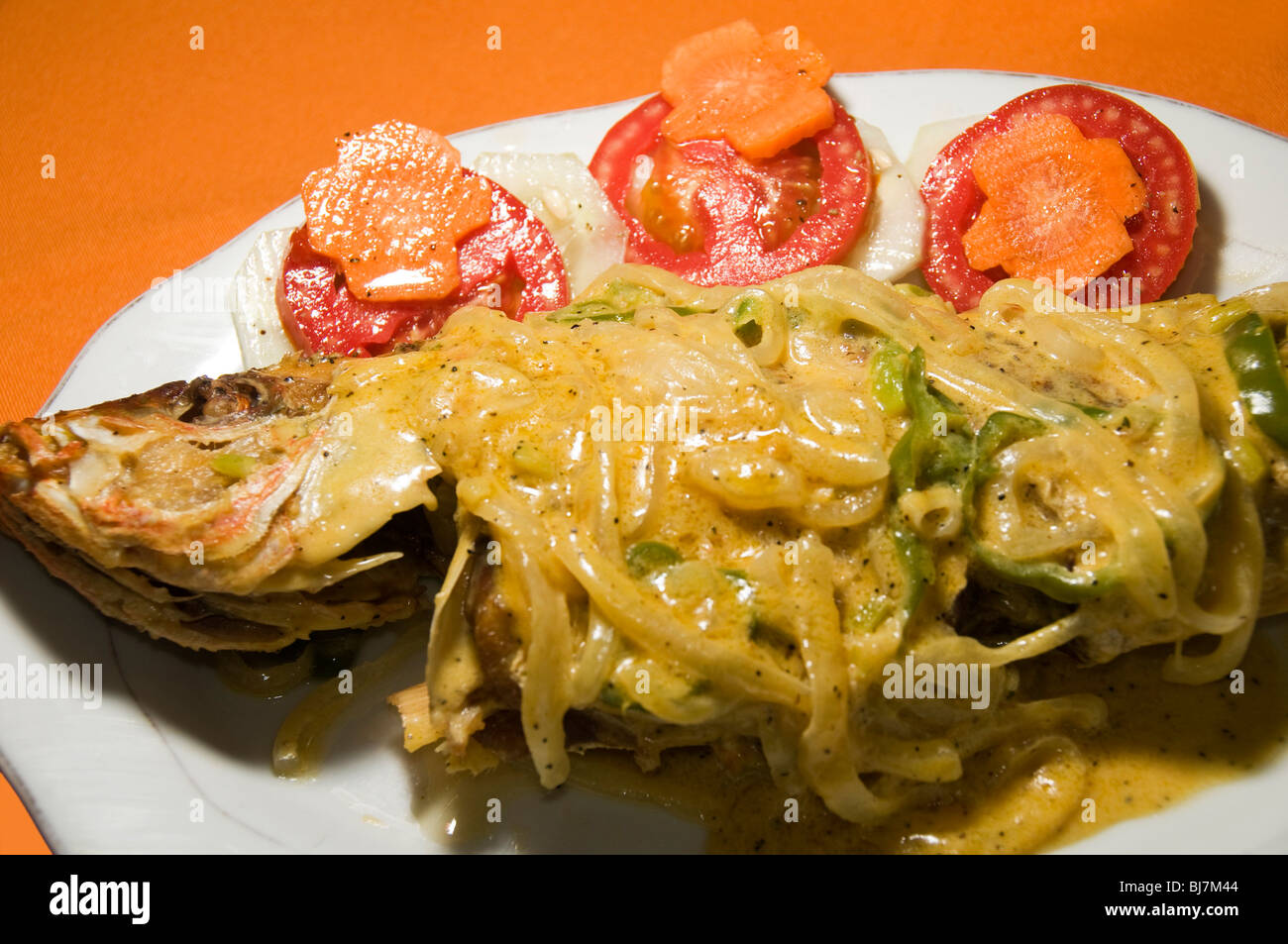 caribena pescado caribbean style kingfish whole cooked with coconut cream sauce and onions and vegetables and nicaraguan salad a Stock Photo
