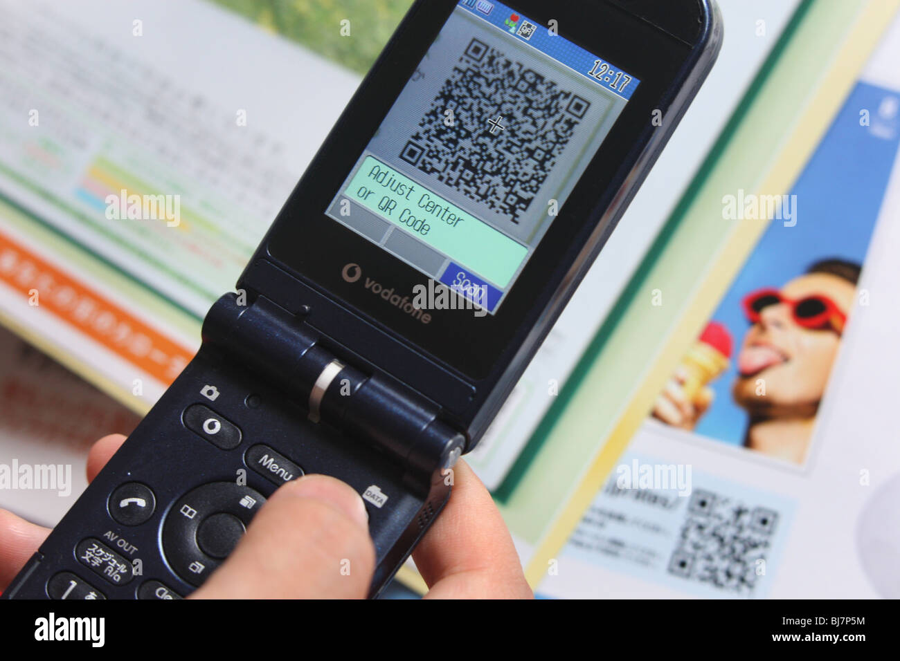 Using a mobile telephone to scan a 'QR Code' ( a square dot matrix barcode) to enable the telephone to download a weblink. Stock Photo