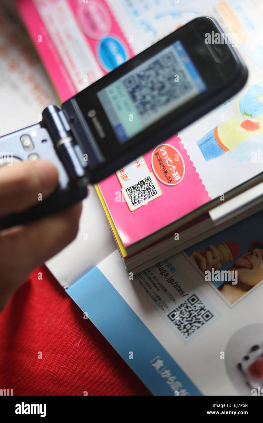 Using a mobile telephone to scan a 'QR Code' ( a square dot matrix barcode) to enable the telephone to download a weblink. Stock Photo