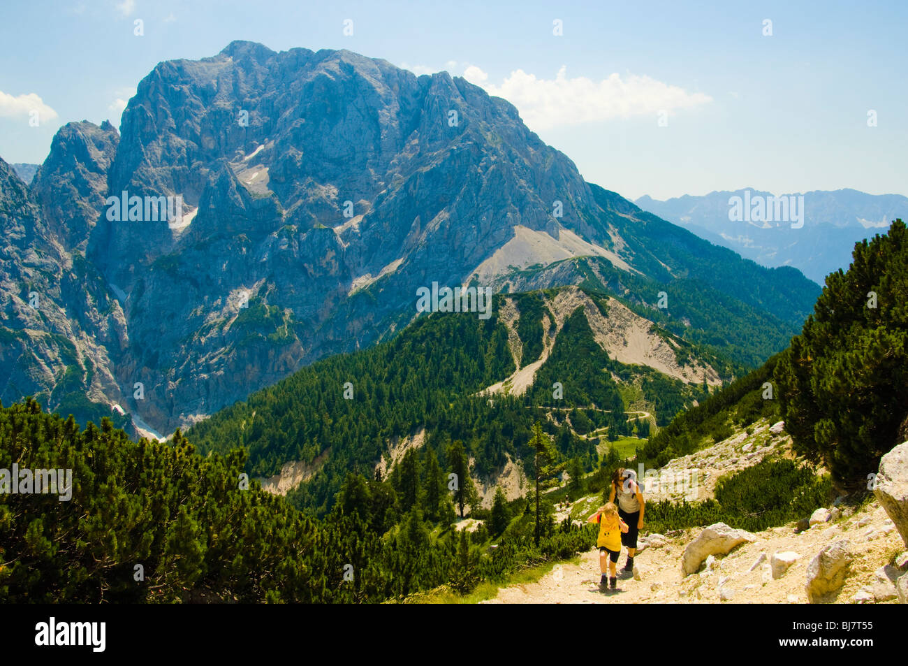 Hikers (mother and child) on trail above the Vrsic Pass in the Julian Alps, Slovenia with the peak of Prisank behind Stock Photo