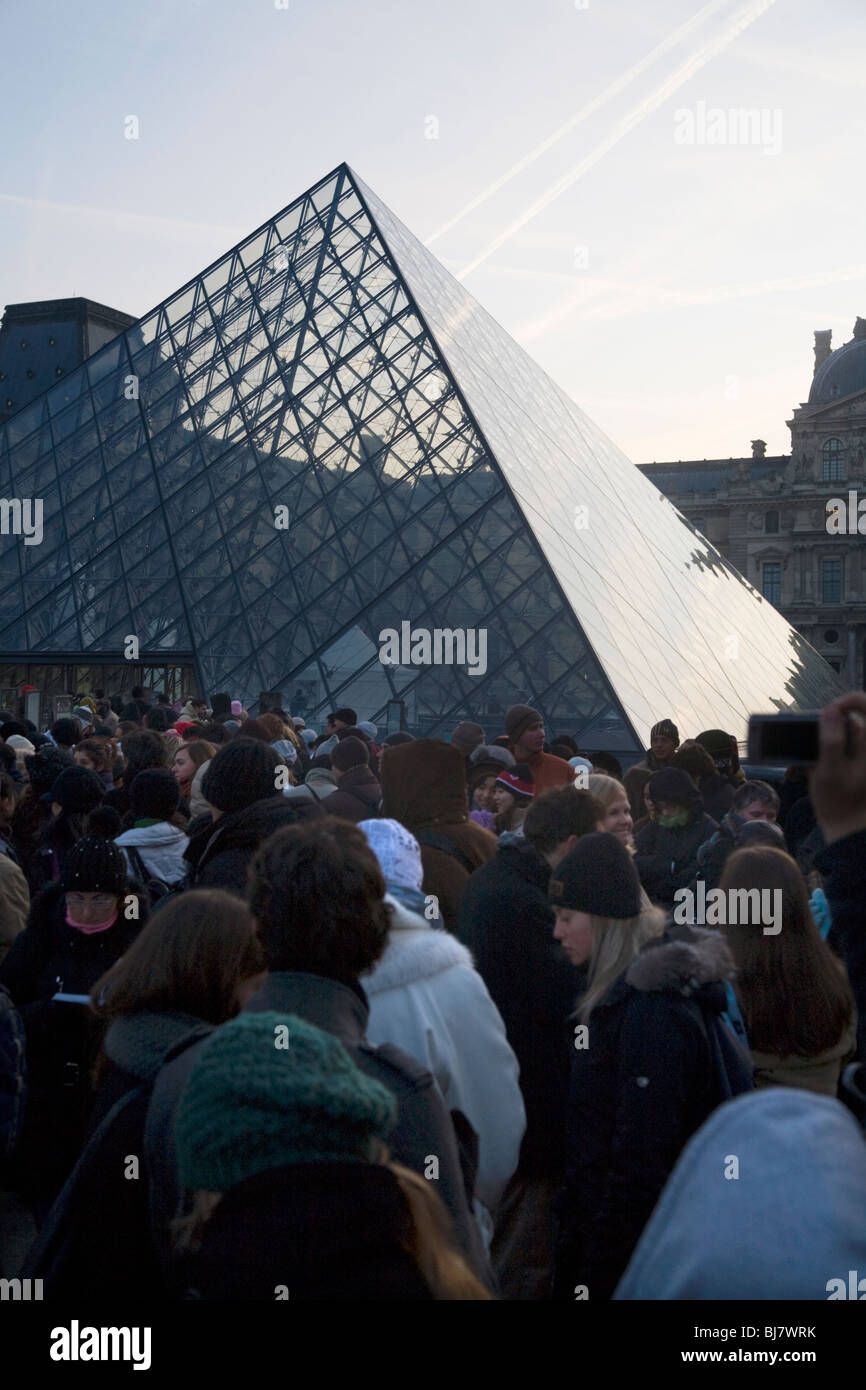 People queue at dawn for free entry to The Louvre Museum / Musee / Palais du Louvre, beside the Glass Pyramid. Paris, France. Stock Photo