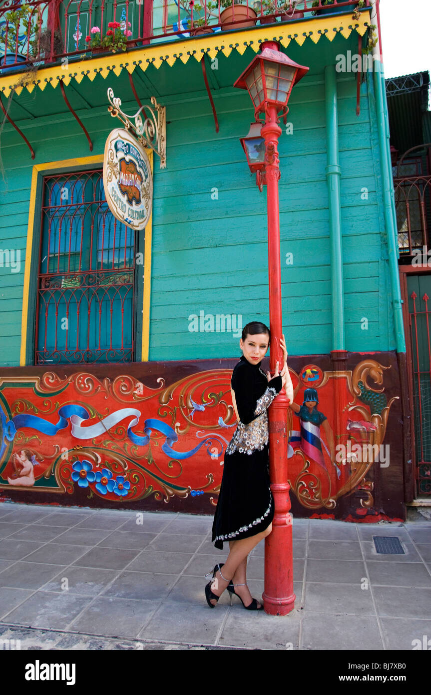 lady tango dancer lean poses on a red street lamp in La Boca in Buenos Aires Argentina Stock Photo