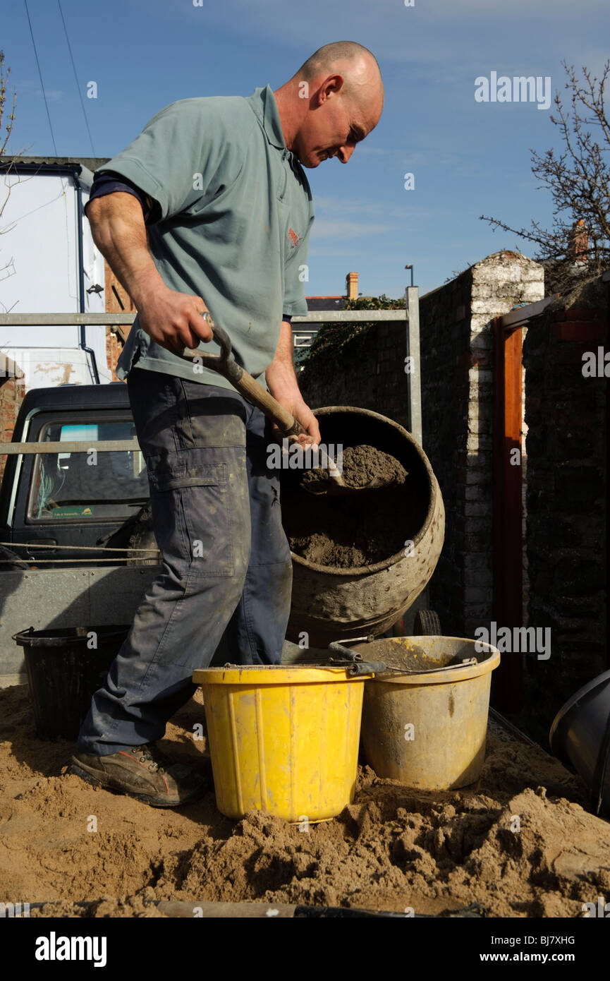 a self employed builder mixing cement , filling buckets, on the back of his truck, UK Stock Photo