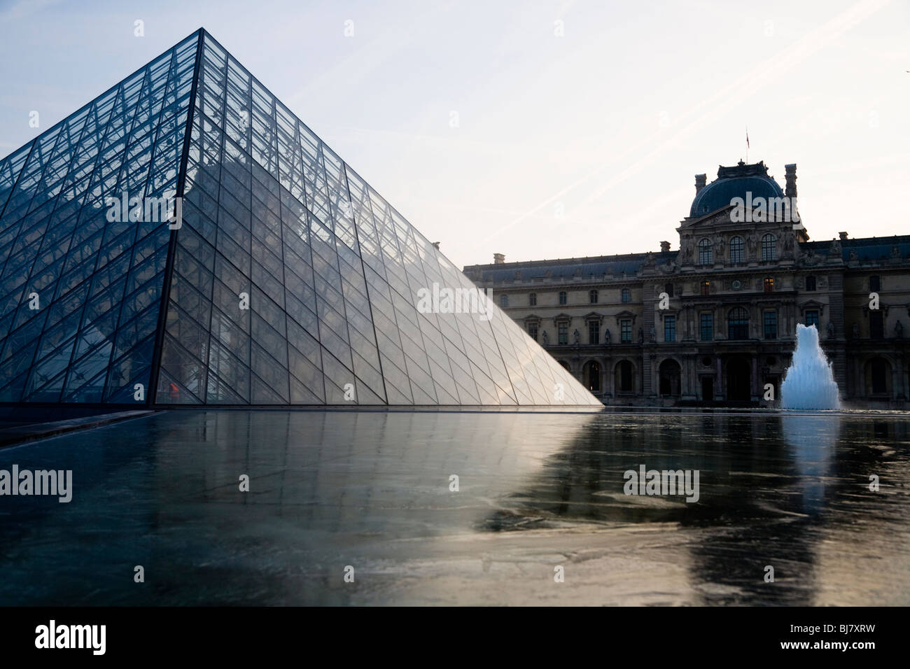 Dawn and winter sunrise over frozen pond near the Glass Pyramid of The Louvre Museum / Musee / Palais du Louvre. Paris, France. Stock Photo