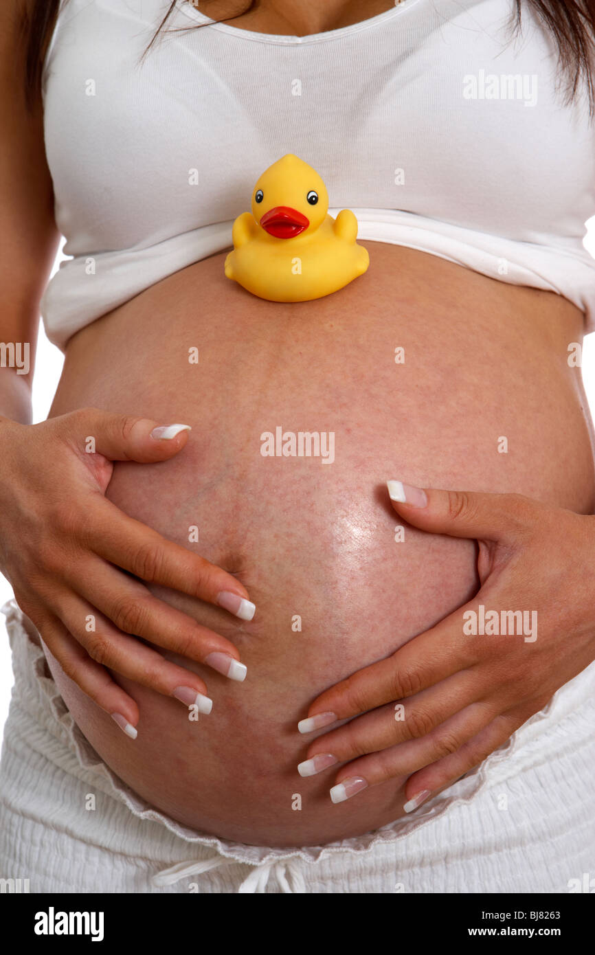 8 month pregnant woman 30 years of age with small yellow childs plastic duck on baby bump Stock Photo