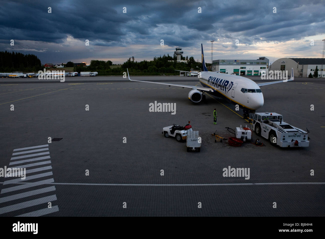 A ryanair aeroplane parked at an airport in evening light under threathening clouds Stock Photo