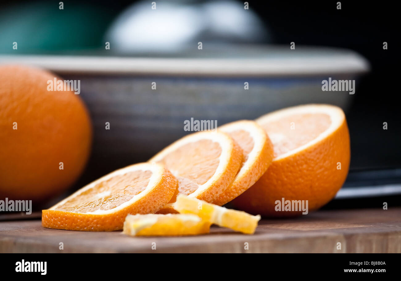 Slices of an orange laying on table with blue bowl in background Stock Photo