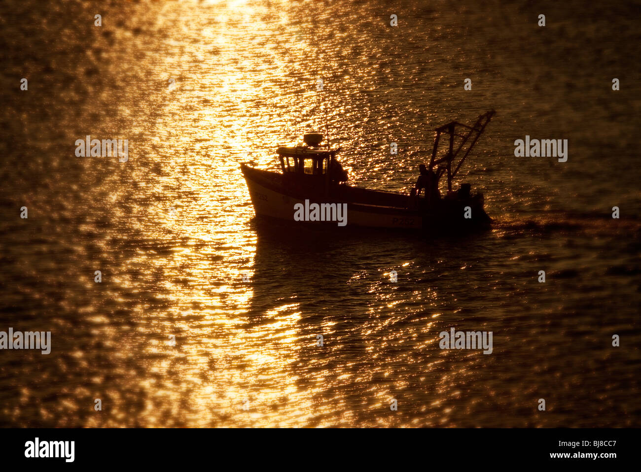 fishing boat heading home at sunset Stock Photo