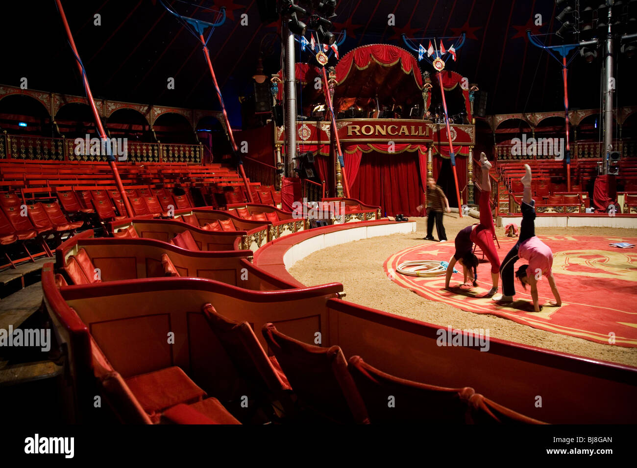 Between shows, two young girls train to be gymnasts under the supervision of a trainer. Circus Roncalli. Munich, Germany Stock Photo