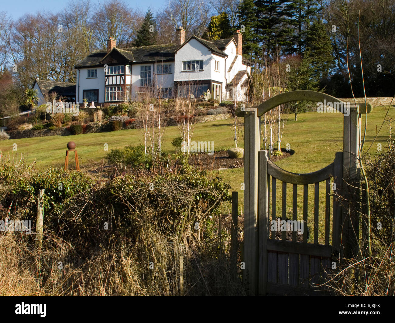 Cheshire, Mottram St Andrew, beautiful detached house with garden sloping to wooden gate Stock Photo