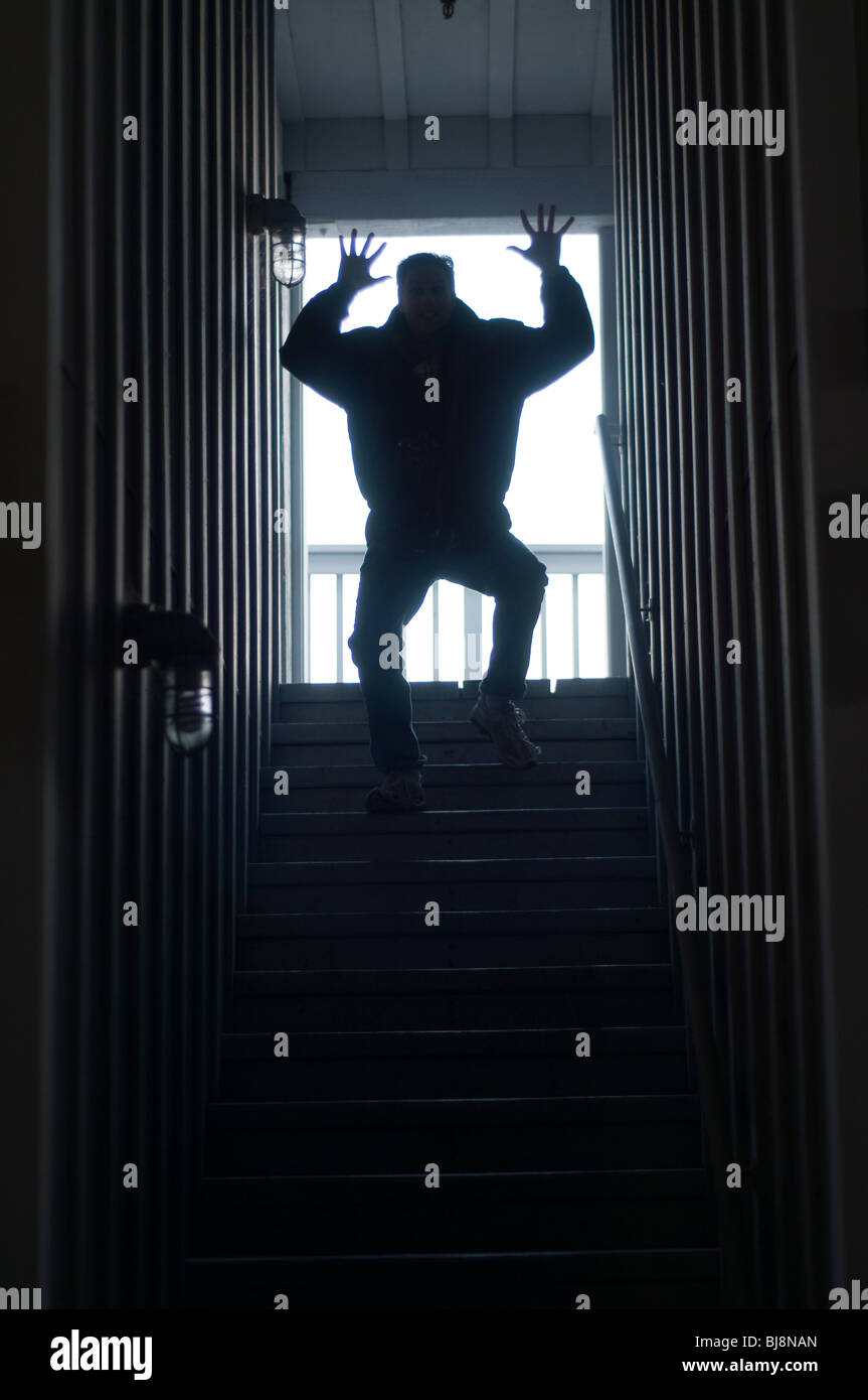 A silhouetted robot like man on stairs with a spooky criminal form Stock Photo