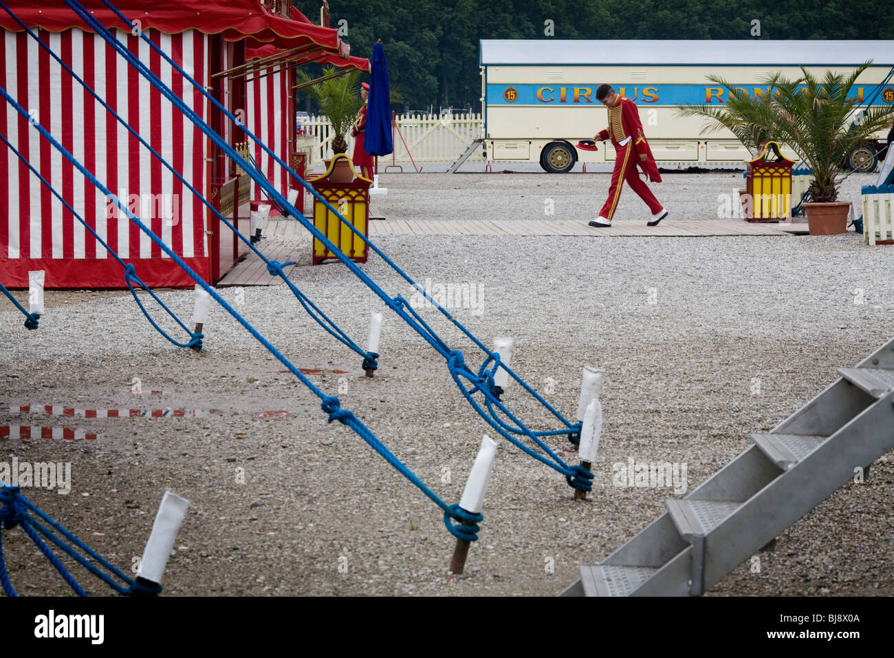 An Usher walks between tents, with a main tent and pegs in front Circus Roncalli. Munich, Germany Stock Photo