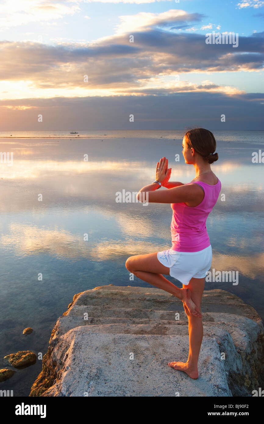 Girl performing yoga pose at end of pier looking into sunset Matabungkay; Batangas; Southern Luzon; Philippines Stock Photo