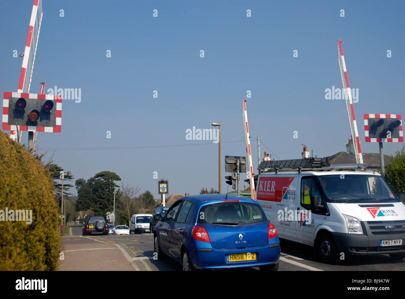 built up traffic flowing as railway level crossing barriers go up Stock Photo