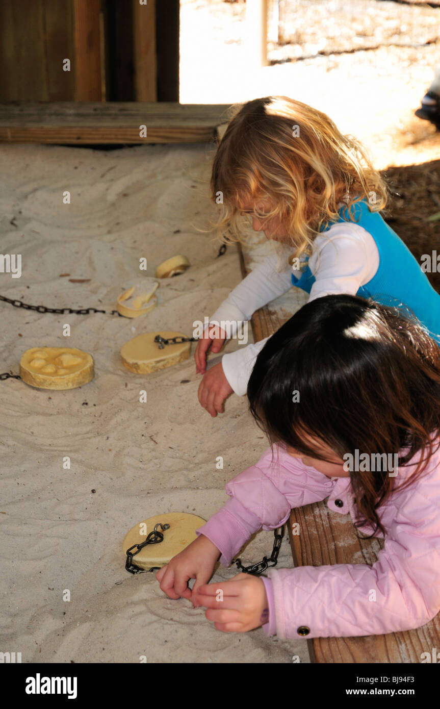 Children enjoy making footprints in the sand using wooden molds at the ...