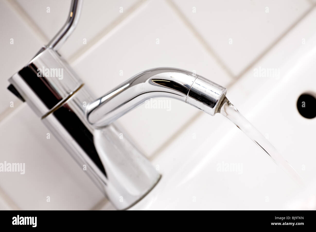 close up of sink and tap with running water in bathroom Stock Photo
