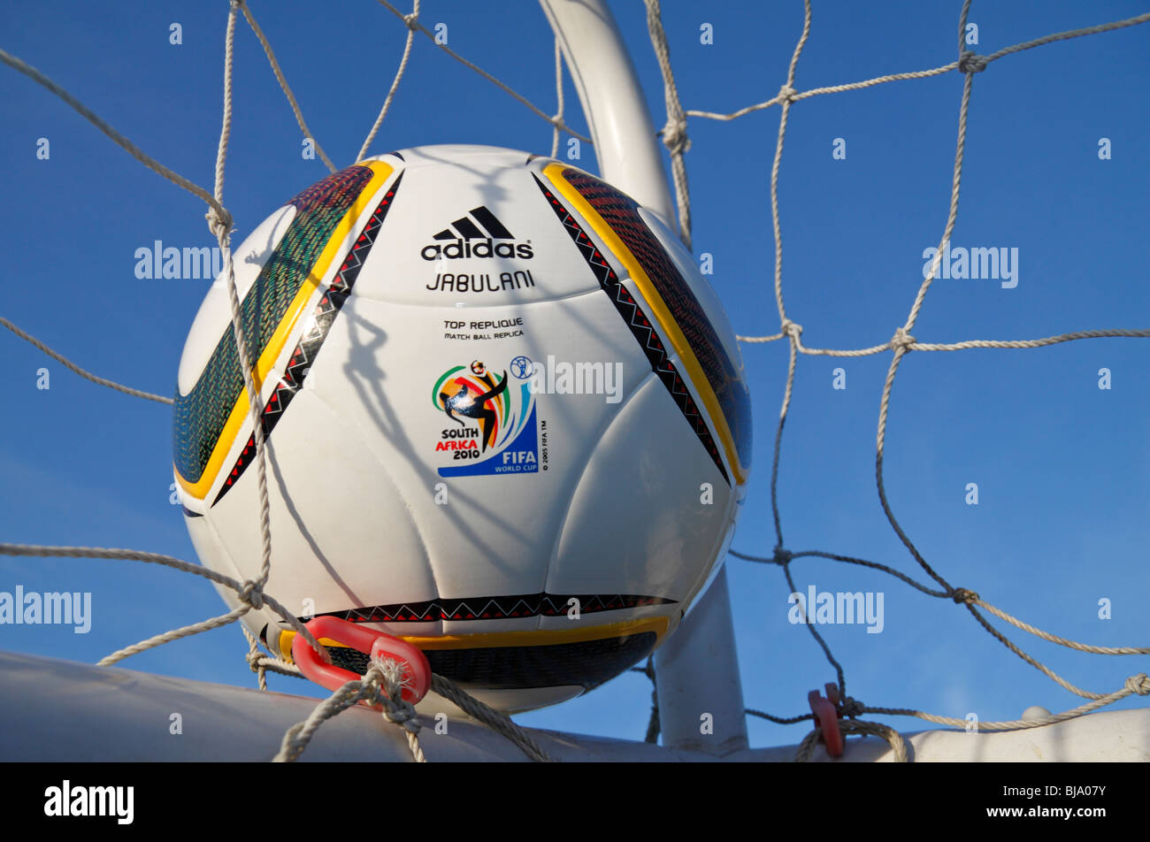 The FIFA 2010 World Cup replica match ball by Adidas, the Jabulani, in the corner of a football net. Stock Photo