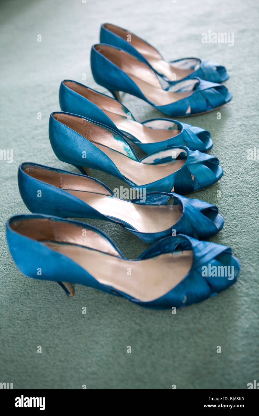 three pairs of blue bridesmaid shoes lined up on green carpet Stock Photo