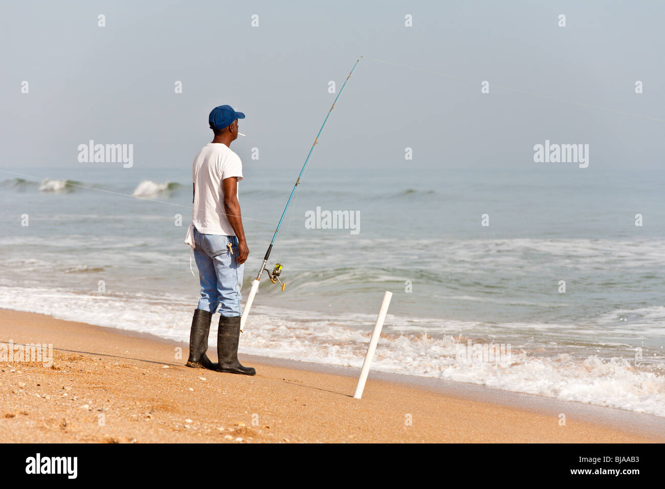 Black man smoking while cigarette while surf fishing in the Atlantic