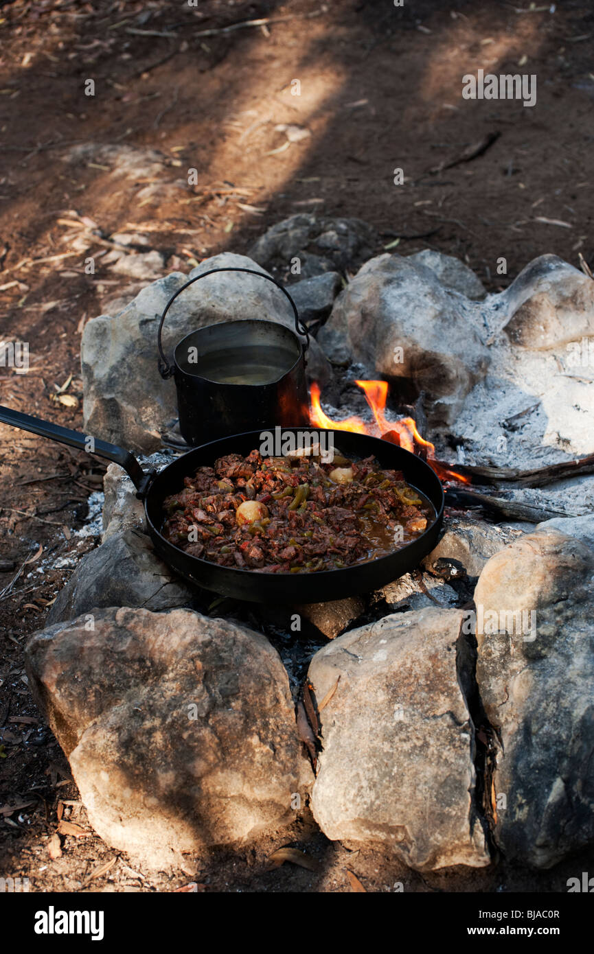 Kangaroo stew and a billy of water simmer over a camp fire on Kangaroo Island, South Australia Stock Photo