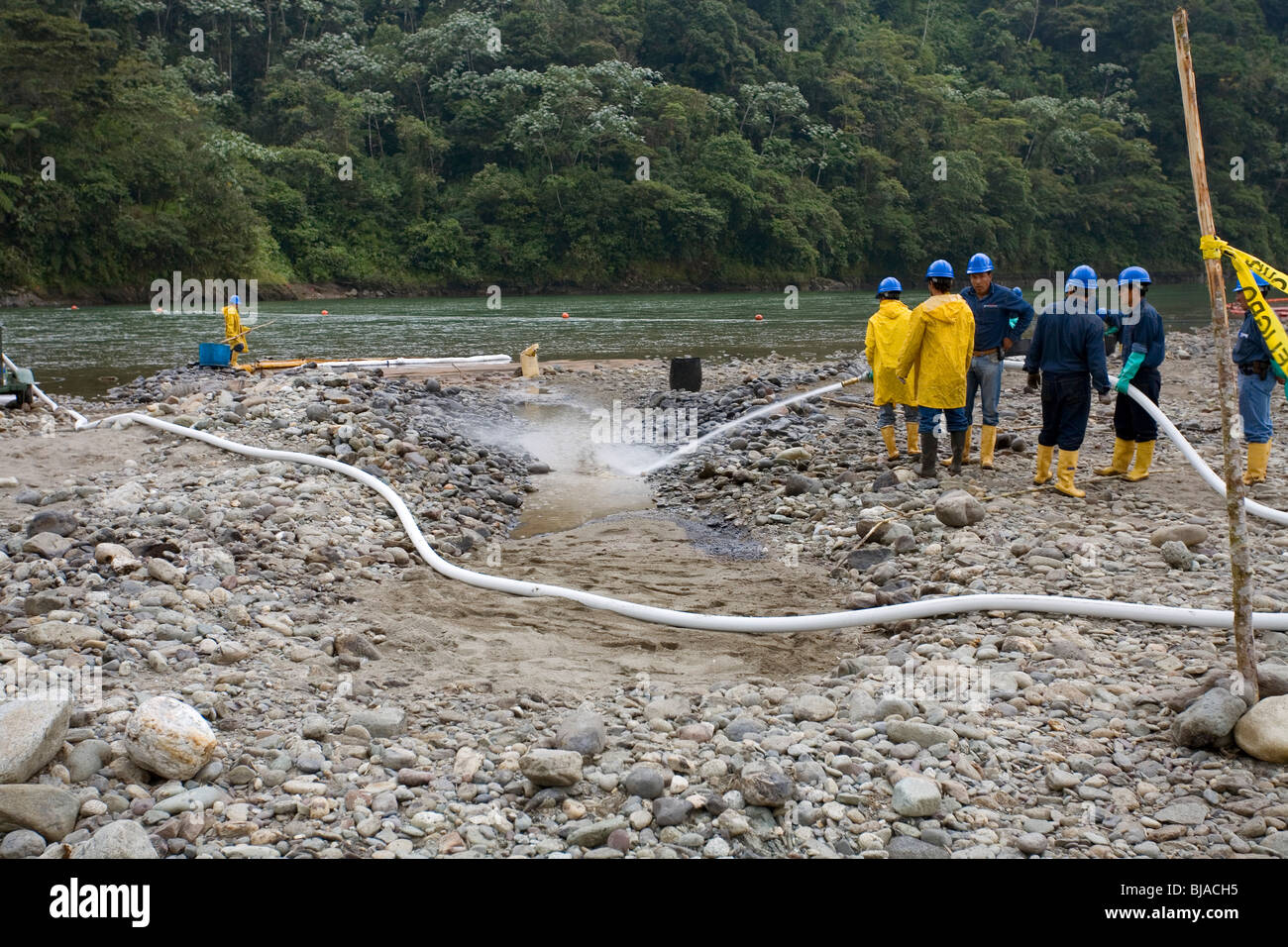 Cleaning up an oil spill on an Amazonian riverbank with a high pressure hose Stock Photo