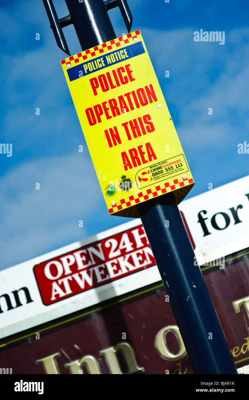 'Police operation in this area' warning sign outside a 24 hour open pub, UK Stock Photo