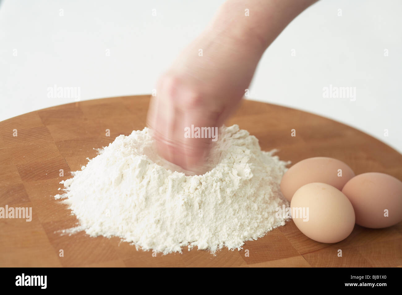 hand forming well into flour to make fresh egg pasta Stock Photo