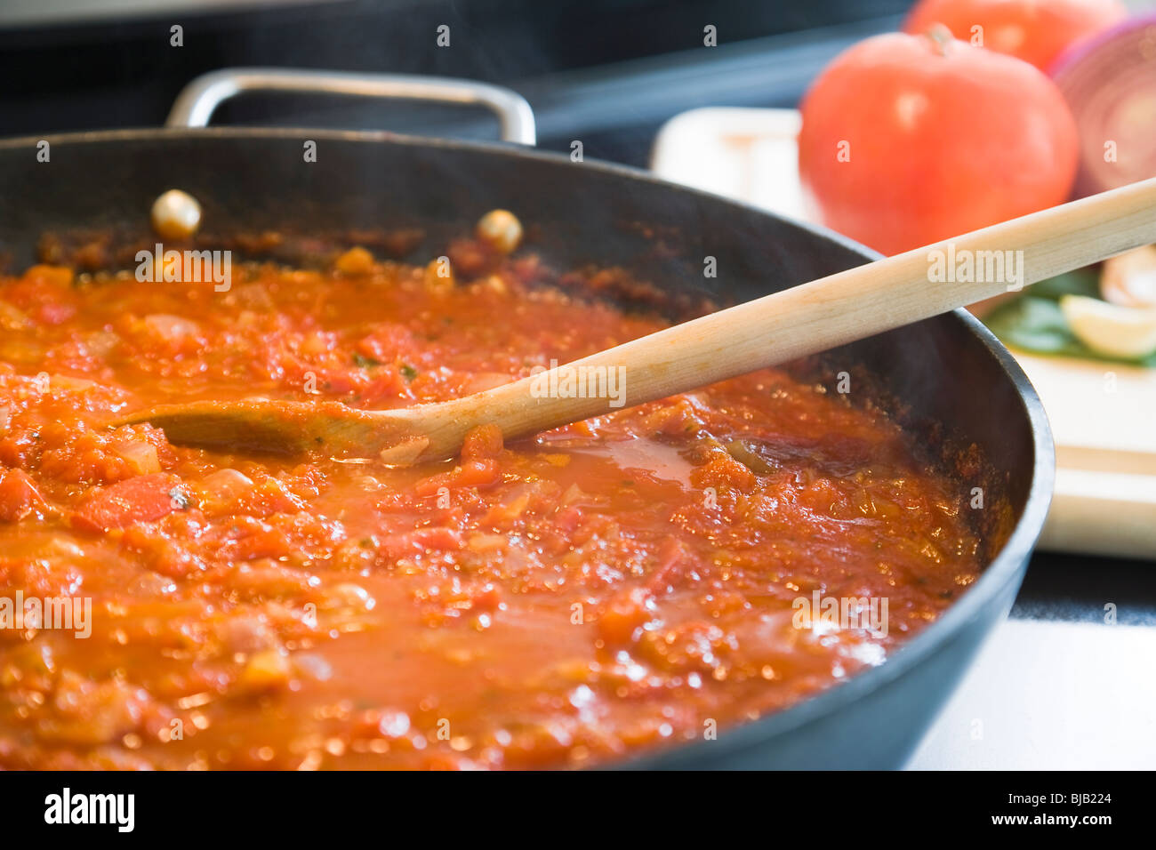 Preparation of tomato sauce on a pan in kitchen. Stock Photo