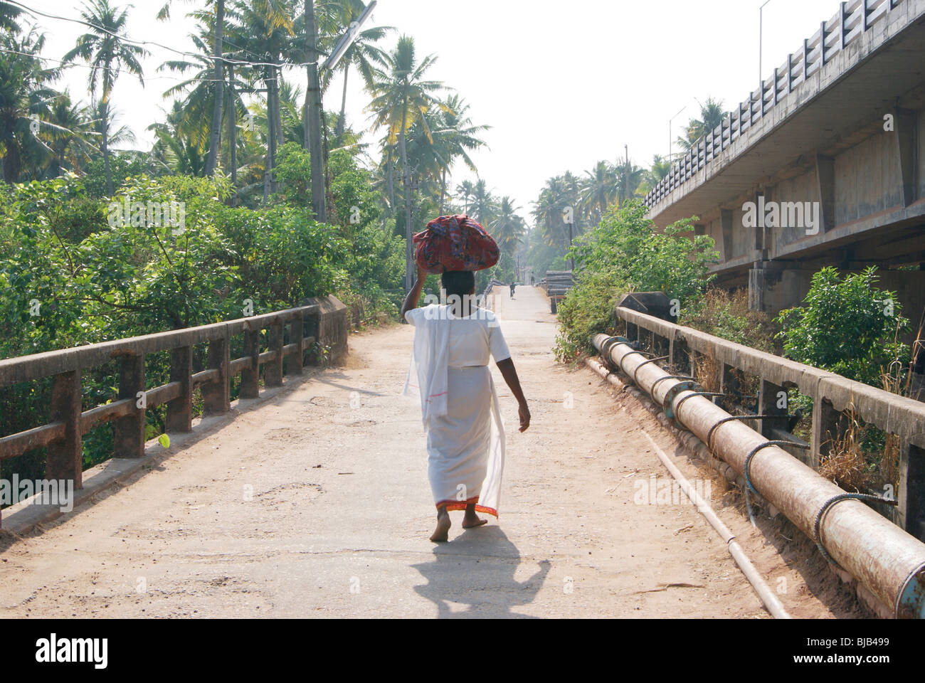 Poor old Native Indian Women carrying old Cloths as a bundle for washing in the River water.A Village scene from Kerala,India Stock Photo