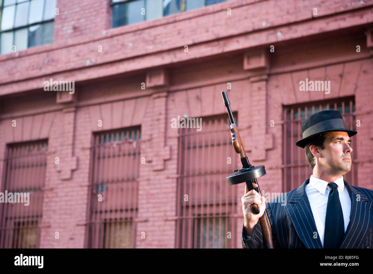 Gangster holding Tommy gun on lookout Stock Photo Alamy