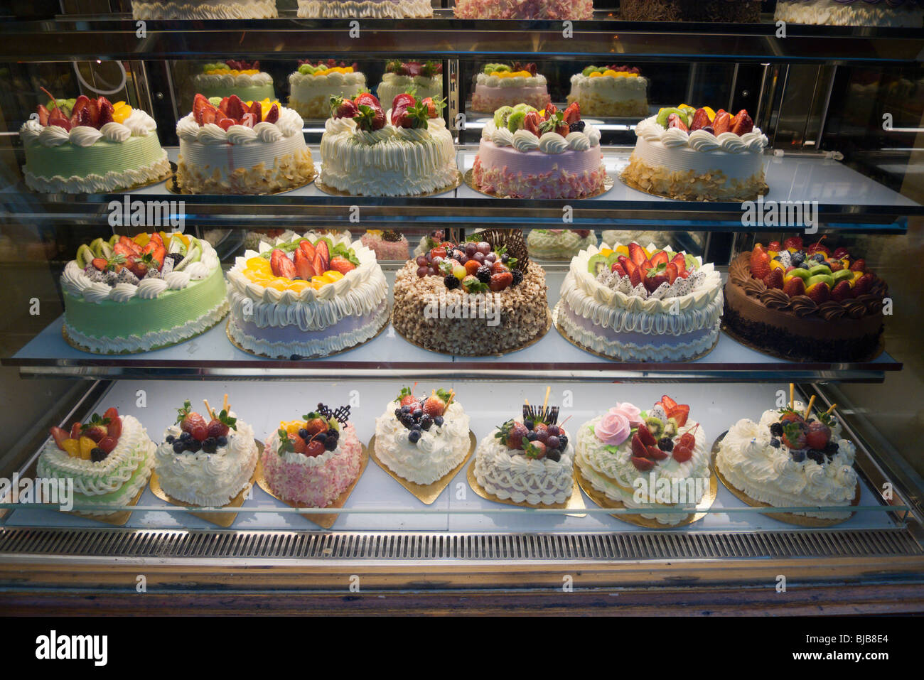 Colourful cakes on display in bakers window Stock Photo Alamy