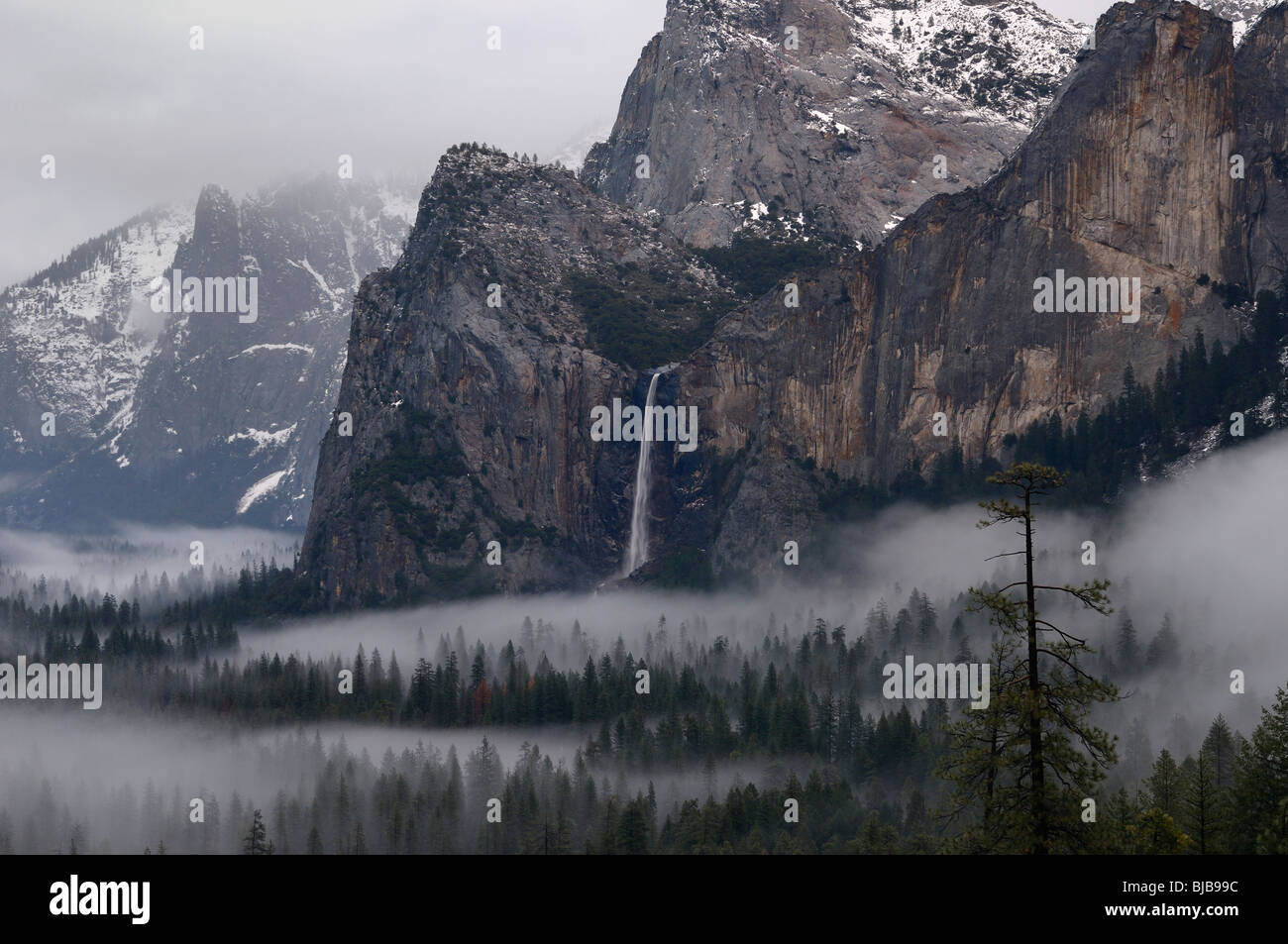 Bridalveil Fall waterfall emptying into clouds and fog in Yosemite Valley after a winter storm seen from Tunnel View Yosemite National Park California Stock Photo