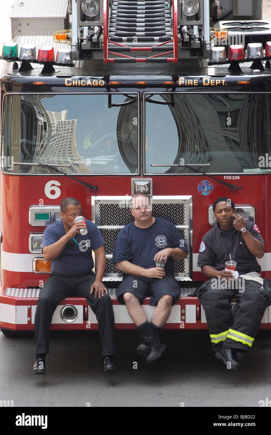 Three firemen sitting on a fire engine bumper and drinking from paper cups Chicago United States of America Stock Photo Alamy