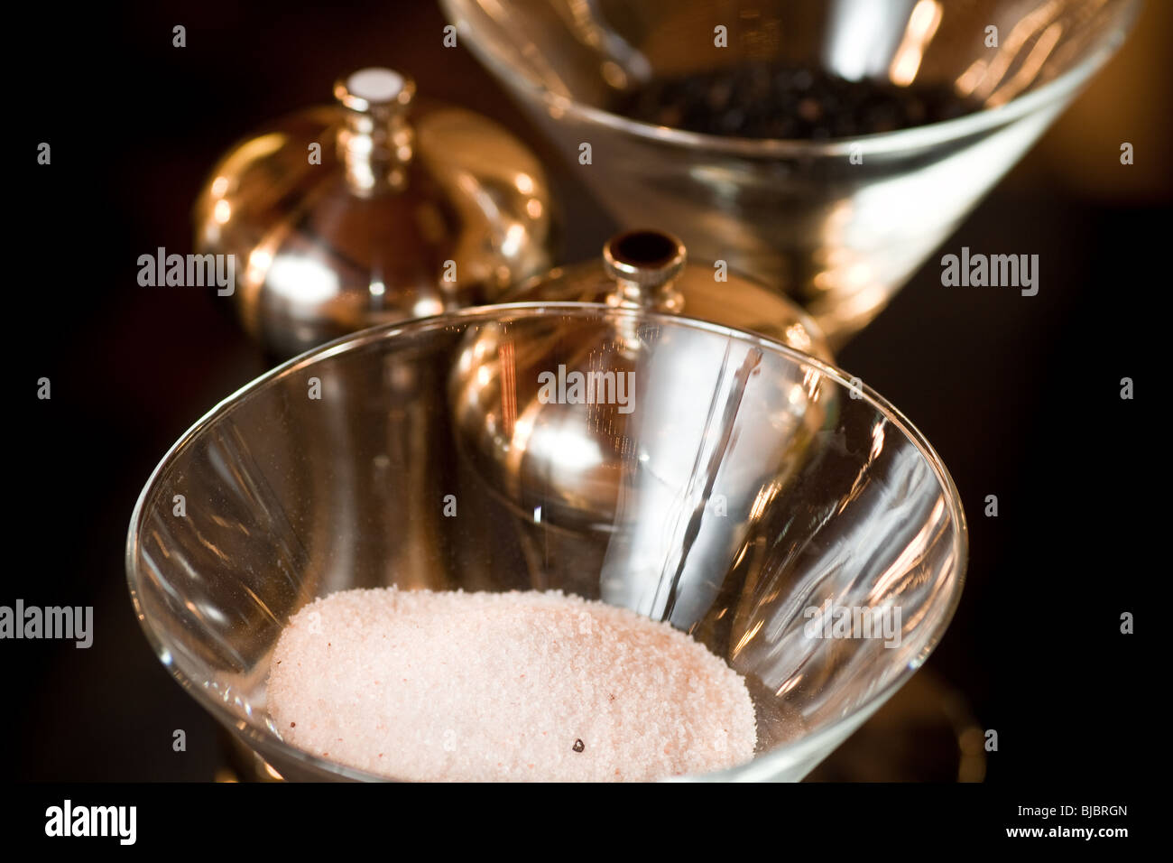 Salt and pepper displayed in open glasses, with metal pepper mills