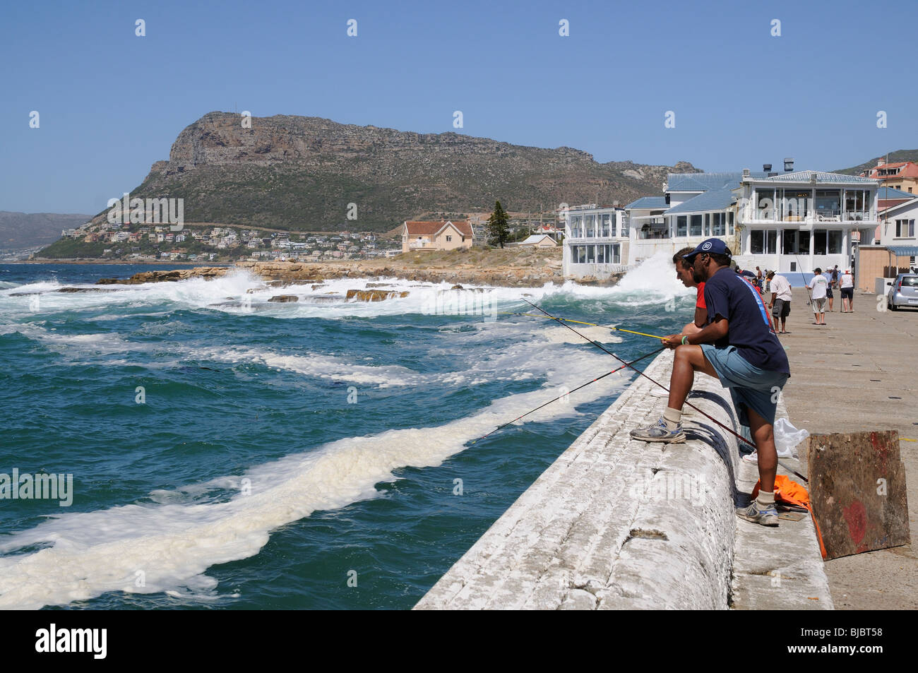 Men fishing from the harbour wall at Fish Hoek a small town in the