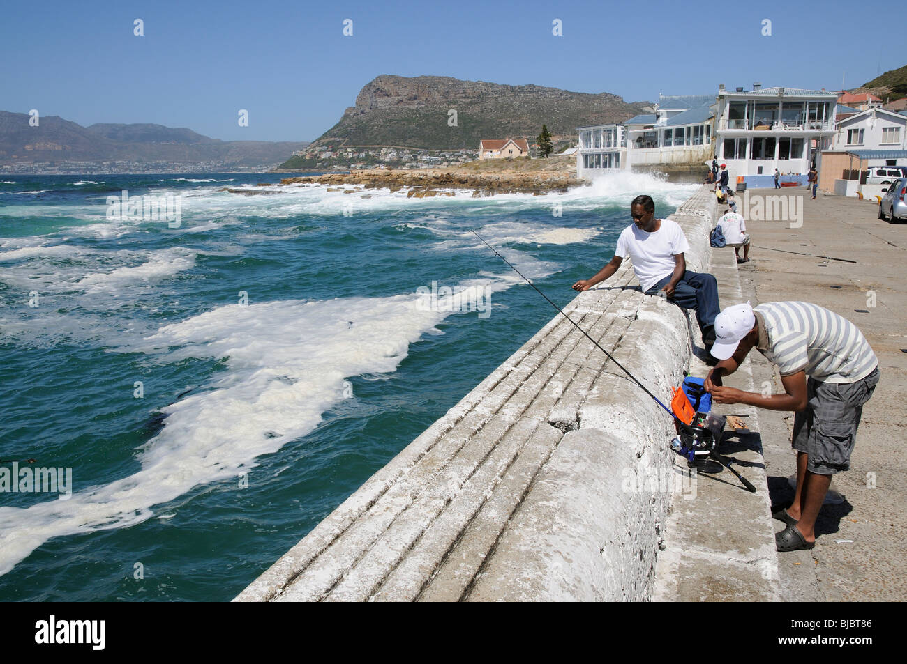 Men fishing from the harbour wall at Fish Hoek a small town in the